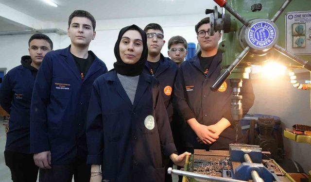 Torna tezgahında öğrencilerine üretimi öğretiyor